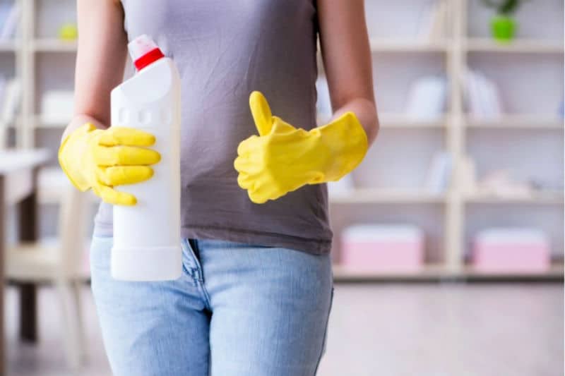 Cosas que las personas limpias hacen todos los días - Mujer sosteniendo una botella de spray y dando pulgar hacia arriba signo
